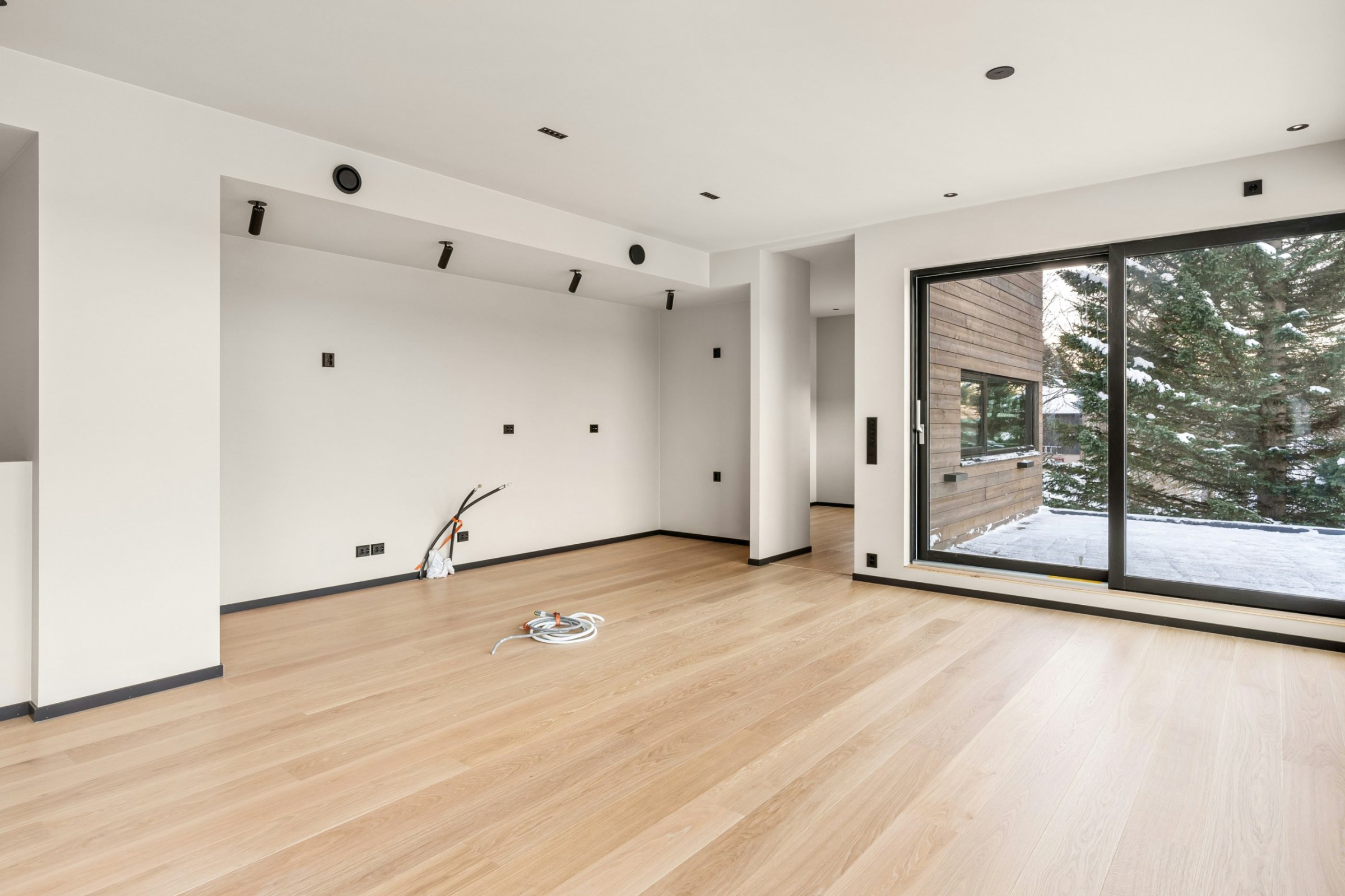 Freshly finished empty room with oak floors and a large sliding window