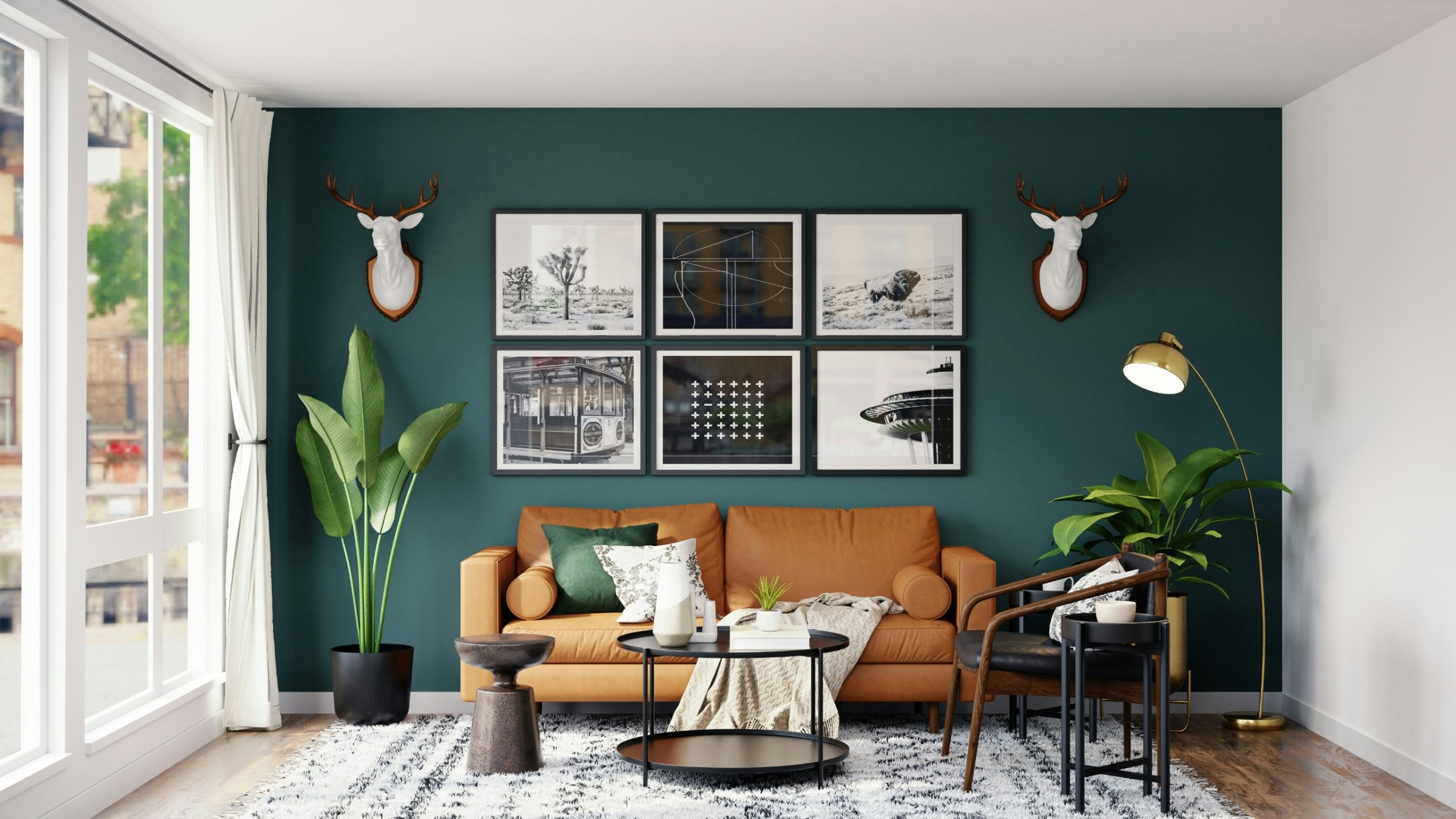 Living room with a deep green accent wall, tan leather sofa and gallery frames